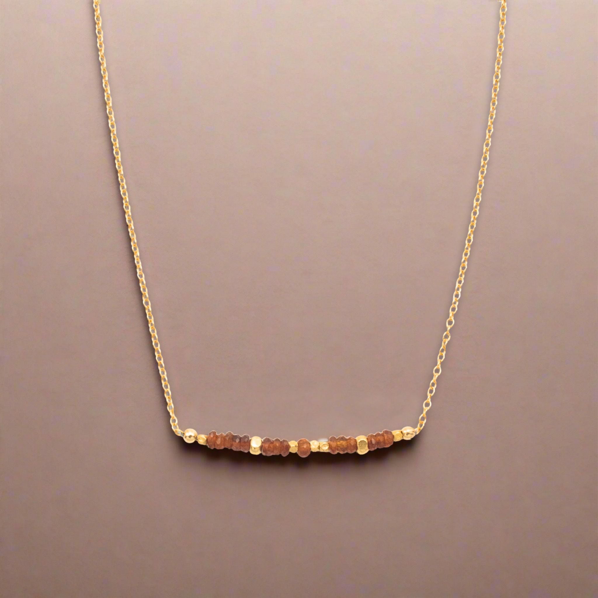 Gold necklace with small beads on a beige background